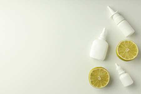 Blank bottles of nasal spray and lime halves on white background