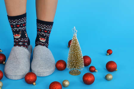 Christmas composition with female legs in Christmas socks on blue backgroundの写真素材