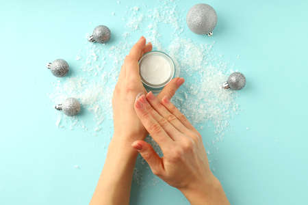 Concept of winter cosmetic with female hands applying cream on blue backgroundの写真素材