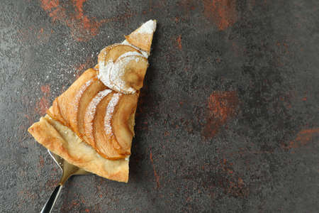 Cake spoon with slice of apple pie on textured background