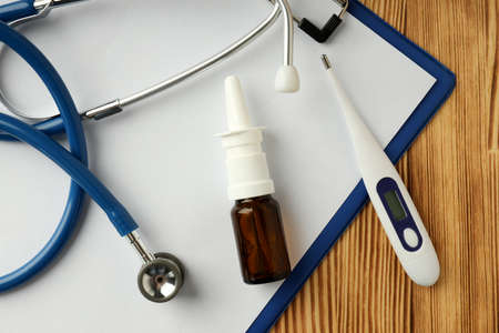 Nasal spray, stethoscope, thermometer and clipboard on wooden backgroundの写真素材