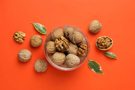 Walnuts in glass jar on orange background