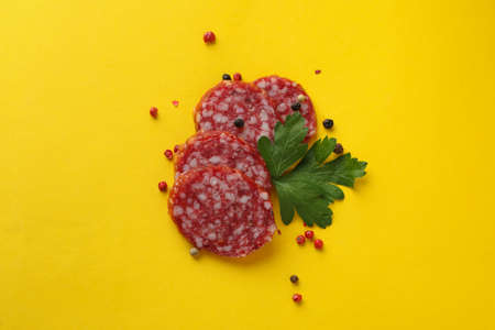 Ð¡oncept of tasty food with salami sausage on yellow background