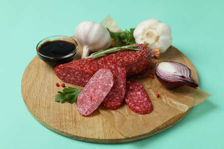 Ð¡oncept of tasty food with salami sausage on mint background