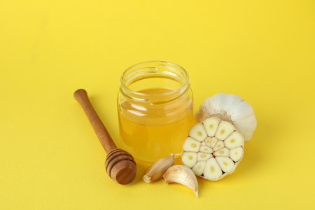 Concept of treatment colds with honey and garlic on yellow backgroundの写真素材