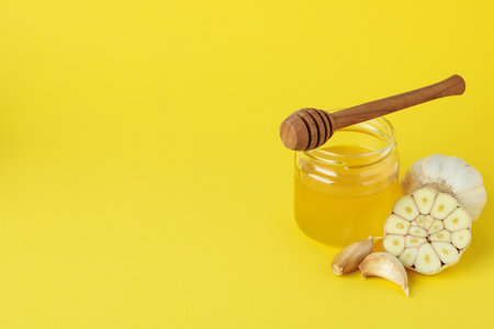 Concept of treatment colds with honey and garlic on yellow backgroundの写真素材