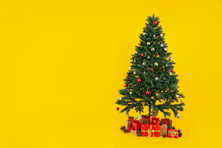 Composition with Christmas tree and gifts on yellow backgroundの写真素材