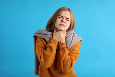 Ill young woman on blue background, seasonal cold concept