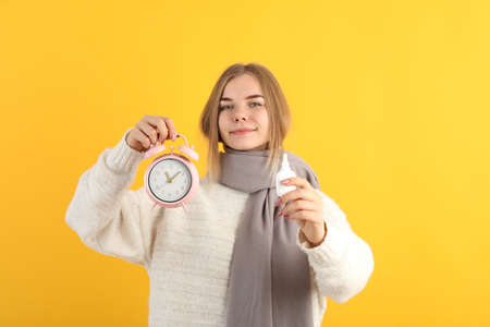 Young woman with nasal drops on yellow background, runny nose concept