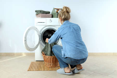 Concept of housework with washing machine and girl against white wallの写真素材