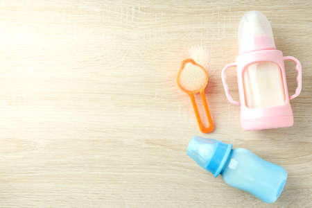 Concept of baby food with powdered milk on wooden background