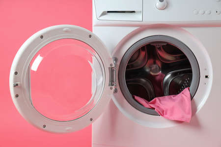 Concept of housework with washing machine on pink background