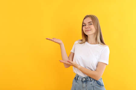Young attractive girl in jeans on yellow background