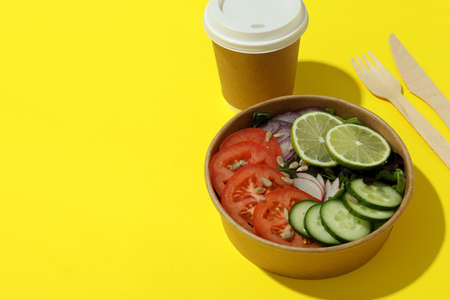 Concept of food delivery with vegetable salad on yellow background