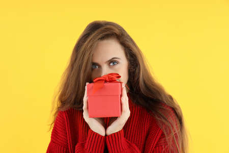 Attractive woman with gift box on yellow backgroundの写真素材