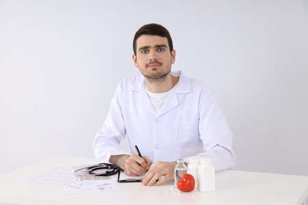 Doctor intern sitting at workplace on white backgroundの写真素材