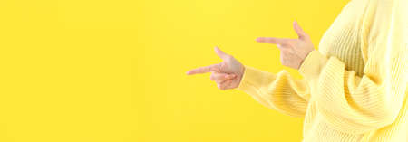 Woman pointing on yellow background, space for textの写真素材