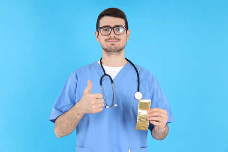 Intern doctor holding condoms on blue backgroundの写真素材