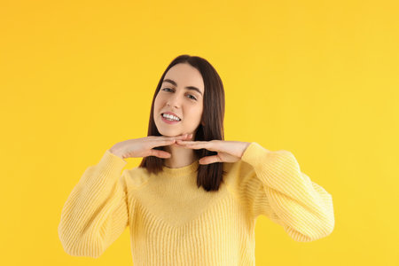 Attractive girl in sweater on yellow backgroundの写真素材