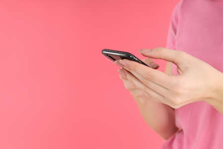 Woman with phone on a pink background, space for textの写真素材