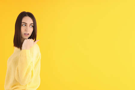 Attractive girl in sweater on yellow backgroundの写真素材