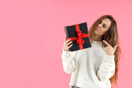 Attractive woman holds gift box on pink backgroundの写真素材