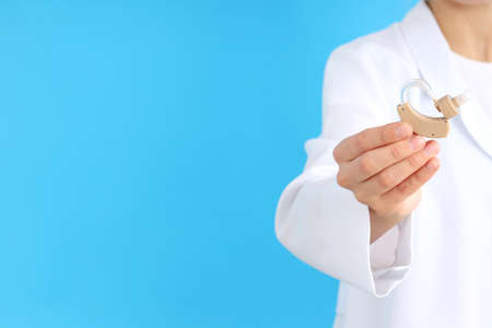 Doctor holding a hearing aid on a blue backgroundの写真素材