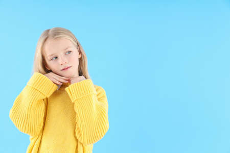 Cute little girl in sweater on blue backgroundの写真素材