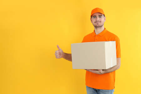 Delivery guy hold box on yellow backgroundの写真素材
