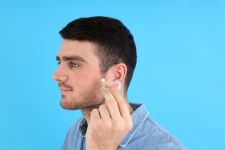 Young man holds hearing aid on blue backgroundの写真素材
