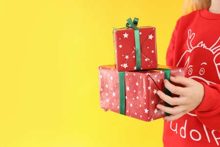 Little girl with Christmas boxes on yellow backgroundの写真素材