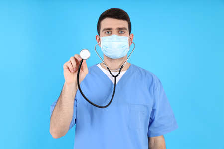 Male nurse in mask with stethoscope on blue backgroundの写真素材