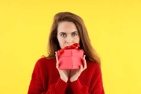 Attractive woman with gift box on yellow backgroundの写真素材