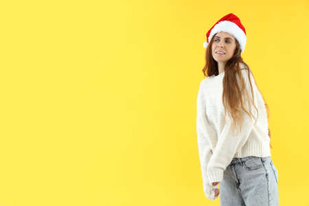 Attractive woman in Santa hat on yellow background