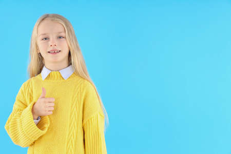 Cute little girl in sweater on blue backgroundの写真素材