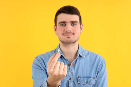 Young man hold hearing aid on yellow backgroundの写真素材