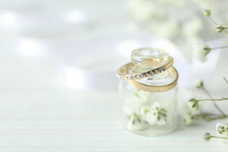 Concept of wedding accessories with wedding rings on white wooden background