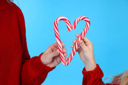 Mom and daughter hold candy canes on blue background