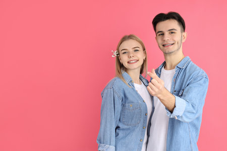 Cute couple with finger heart on pink backgroundの写真素材