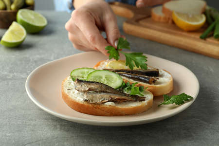 Concept of tasty snack with sandwiches with sprats on gray textured tableの写真素材
