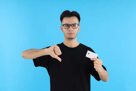 Attractive guy with credit card on blue background