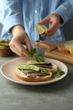 Concept of tasty snack with sandwiches with sprats on gray textured tableの写真素材