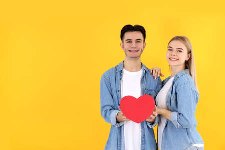 Cute couple with heart on yellow background