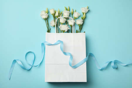 Paper bag with roses and ribbon on blue backgroundの写真素材