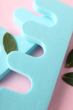 Nail separators and leaves on pink background