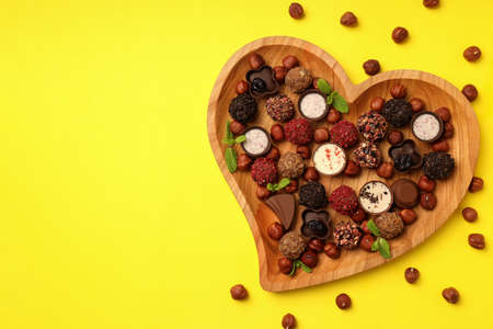 Concept of sweets with chocolate candies on yellow backgroundの写真素材