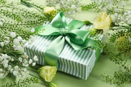 Gift box with flowers on green backgroundの写真素材