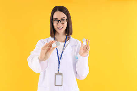 Female doctor with thermometer gun on yellow backgroundの写真素材