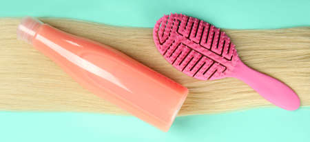 Female hair with shampoo and hairbrush on mint backgroundの写真素材