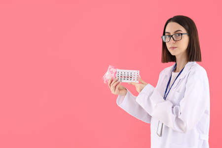 Female doctor with period calendar and pads on pink backgroundの写真素材